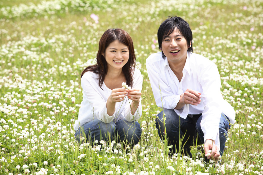 公園で白つめ草を摘むカップル